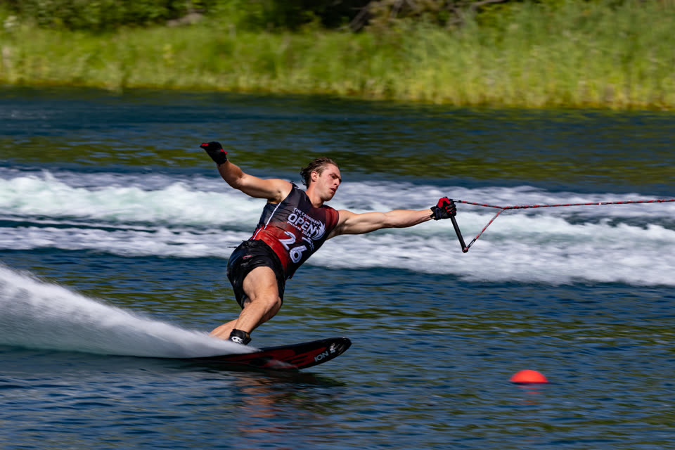 Slalom skier at full stretch reaching for the buoy